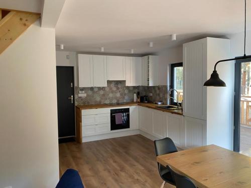 a kitchen with white cabinets and a wooden table at Domek Bartoszylas z sauną i balią in Bartoszylas