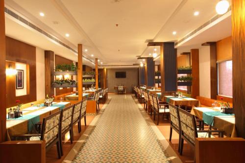 a restaurant with tables and chairs and a long corridor at National Park residency in Ettumānūr