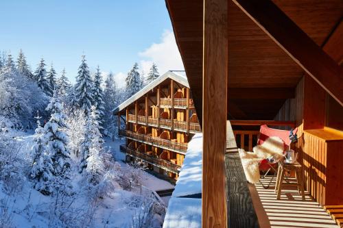 a log cabin in the snow with a balcony at Hôtel L'Arboisie in Megève