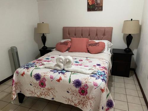 a bedroom with a bed with a pink and white comforter at Apartment 10 minutes by the SJO airport - in Alajuela