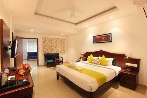 a hotel room with a bed and a television at National Park Residency Kottayam in Ettumānūr