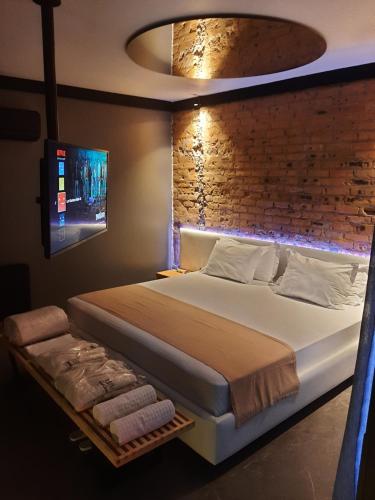 um quarto com uma cama grande e uma parede de tijolos em LUV Gardens Motel - Adults Only em Caxias do Sul