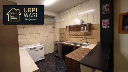 a small kitchen with a sink and a stove at Urpi Wasi Backpackers in Puno