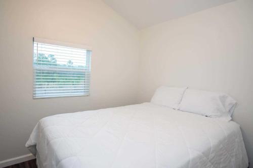 a white bed in a white room with a window at Jellystone Park Tyler in Tyler