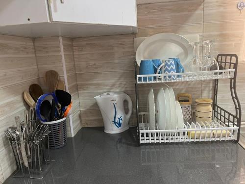 a kitchen with a shelf with plates and utensils at Koselig California in Nanyuki
