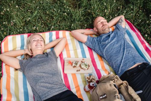 two people laying on a blanket on the grass at Stock & Stein Lodges in Bad Gleichenberg