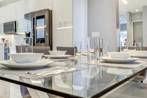 a glass table with white plates and utensils on it at Deco Delight - Central Hub in Miami