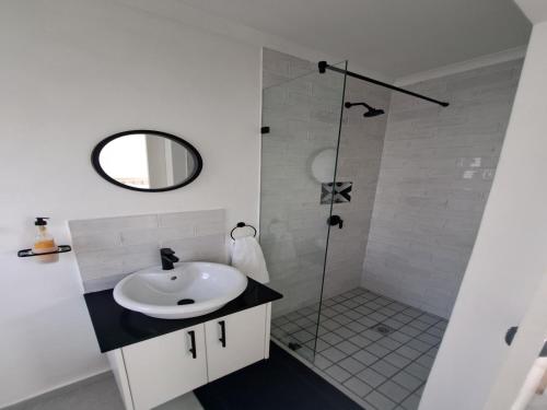 a white bathroom with a sink and a shower at 6 on Third in Stompneusbaai