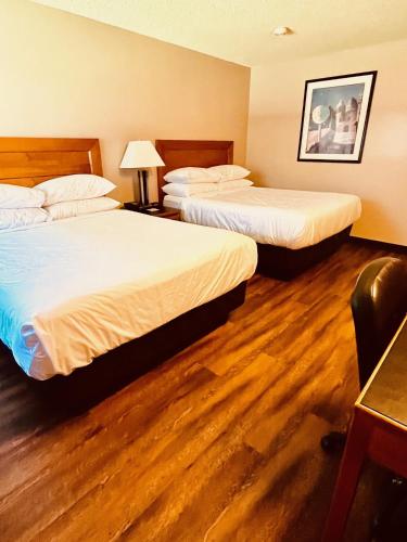 two beds in a hotel room with wood floors at Royal Hotel Lloydminster in Lloydminster
