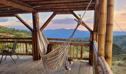 a woman sitting in a hammock on a porch at LA MARQUESA PACORA in Pácora
