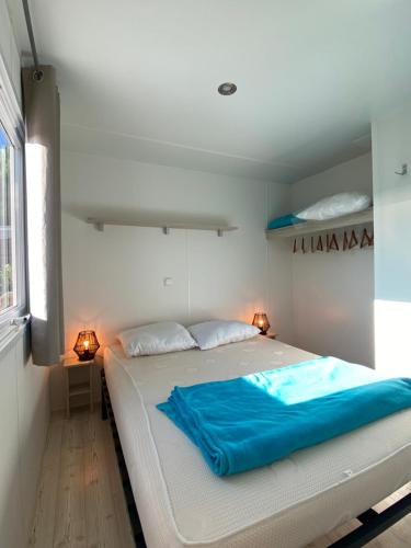 a bedroom with a large white bed with blue sheets at Mobil-home 5 personnes dans camping Mar Estang 4 étoiles avec accès à la plage in Canet-en-Roussillon