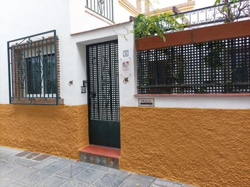 un bâtiment avec un mur noir et jaune et une porte dans l'établissement Casa de la Portuguesa, bonita terraza con barbacoa, à Güéjar-Sierra