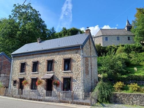 una vieja casa de piedra con una valla delante de ella en La Maison d'Anne-Marie, en Beauraing