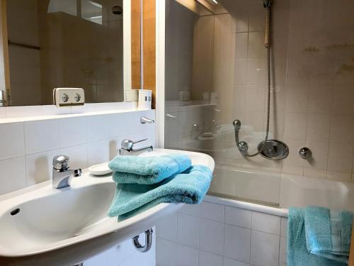 a bathroom with a sink and a shower with blue towels at Ferienwohnung Alina in Kressbronn am Bodensee