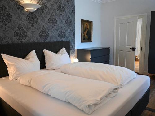 Una cama con sábanas blancas y almohadas. en Ferienwohnung Lindauer Löwe, en Lindau