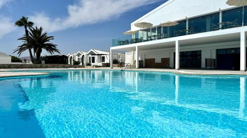a large blue swimming pool in front of a building at Caleta Dorada in Caleta De Fuste