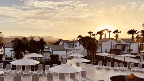 a resort with white umbrellas and palm trees at Caleta Dorada in Caleta De Fuste
