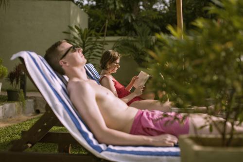 un hombre y una mujer sentados en una silla leyendo un libro en Hotel Athgira en Udawalawe