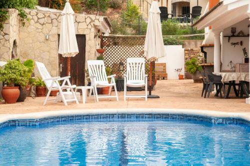 een zwembad met 2 stoelen en parasols bij Villa Nuis L'Estartit. Piscina y jardín privados. Ideal para familias in Torroella de Montgrí