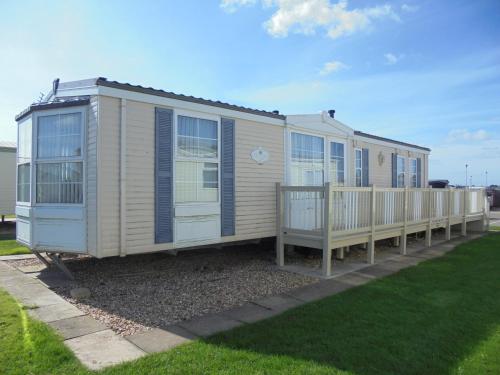 a mobile home with a porch and a fence at Golden Anchor : Ovation 4 Berth, Wrap Around Decking in Chapel Saint Leonards