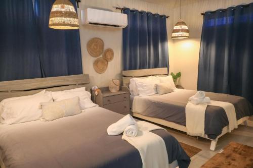 two beds in a bedroom with blue drapes at Casa Arrecife 28 in Cabo Rojo