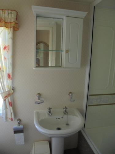 a bathroom with a sink and a mirror at Golden Anchor : Ovation 4 Berth, Wrap Around Decking in Chapel Saint Leonards