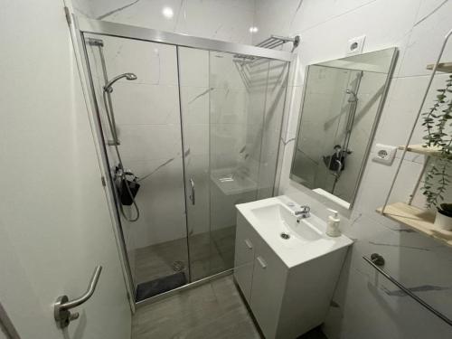 a bathroom with a glass shower and a sink at Stone Rose House in Nazaré