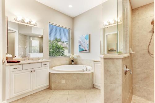 a bathroom with a tub and a sink and a shower at Modern home w screened pool, hot tub, & comm amenities! in Naples