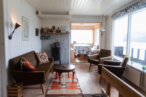 een woonkamer met een bank, stoelen en een tafel bij Cottage with stunning view of the sea and islands. in Leynar