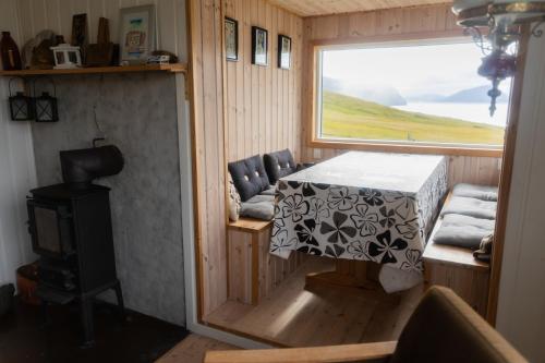 a tiny house with a table and a window at Cottage with stunning view of the sea and islands. in Leynar