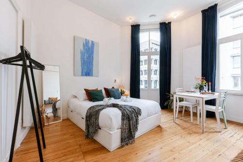 a white bedroom with a bed and a table at 'The Jungle' Studio in the heart of Ghent in Ghent