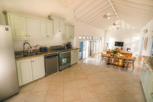 cocina grande con armarios blancos y mesa de comedor en Amazing mountain top home with stunning views!, en Bahía Marigot