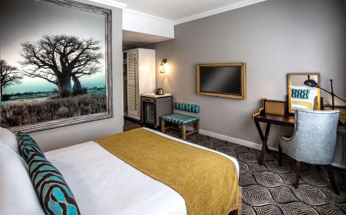 a hotel room with a bed and a desk and a computer at Southern Sun Ridgeway Lusaka in Lusaka