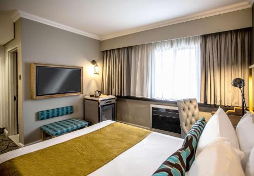 a hotel room with a bed and a flat screen tv at Southern Sun Ridgeway Lusaka in Lusaka