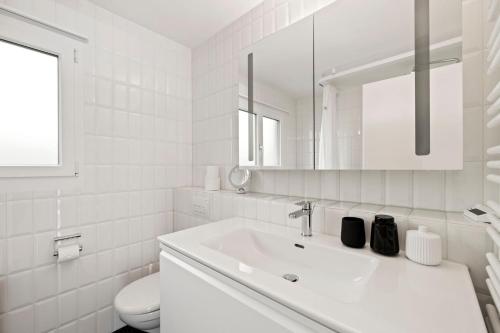 Baño blanco con lavabo y aseo en Sunny Design Chalet in Engelberg with spectacular view on Mount Titlis en Engelberg