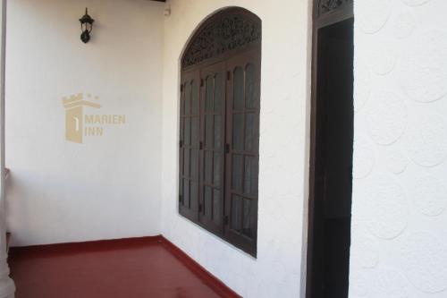 une porte dans une chambre blanche dotée d'un sol rouge dans l'établissement Marien Inn, à Galle