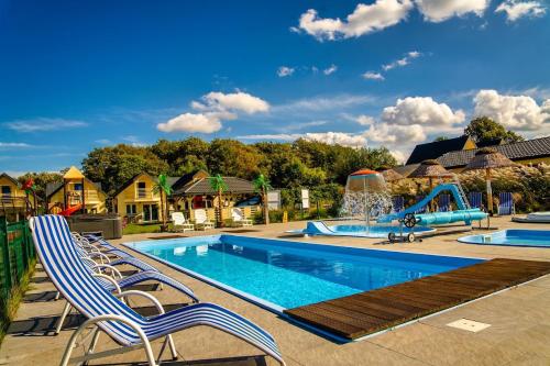a swimming pool with chairs and a water park at Perłowe Wzgórze in Ustronie Morskie