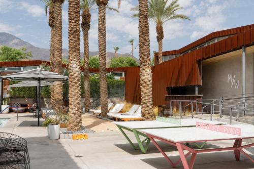 a patio with palm trees and tables and chairs at ARRIVE Palm Springs - Adults Only in Palm Springs