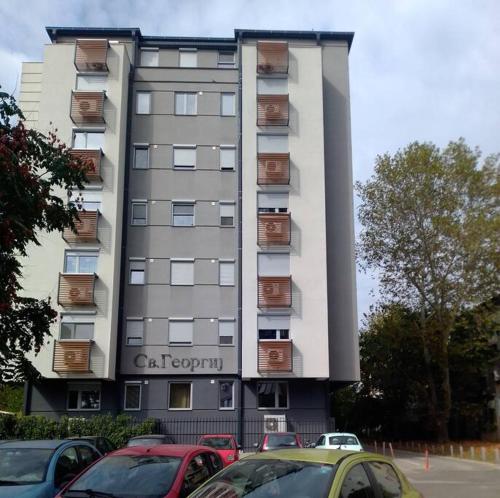 a tall building with cars parked in front of it at King-size bed, Free parking, kitchenette, wifi apartments in Skopje