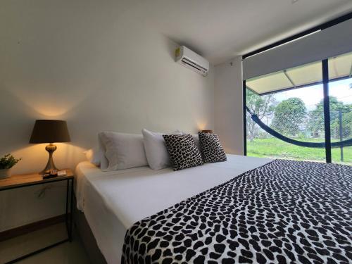 Schlafzimmer mit einem schwarzen und weißen Bett und einem Fenster in der Unterkunft Amazonia Deluxe Lake Condo in Leticia