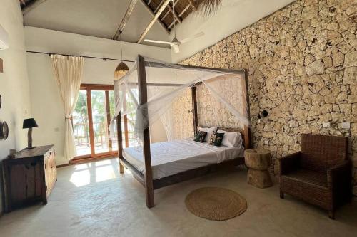 ein Schlafzimmer mit einem Himmelbett in einer Steinwand in der Unterkunft Ocean Front Villa with pool, Zanzibar in Pingwe