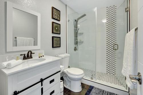 a white bathroom with a shower and a toilet at The Gardens - Luxury Retreat with Pool & Game Room in Miami Gardens