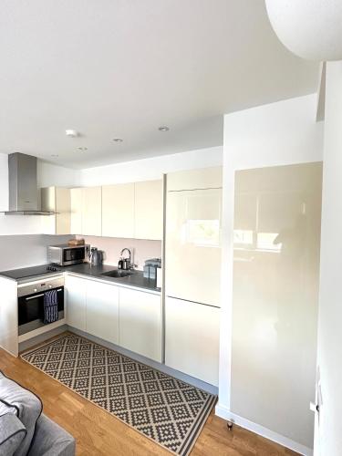 una cocina blanca con armarios blancos y fregadero en Holloway Studio en Londres