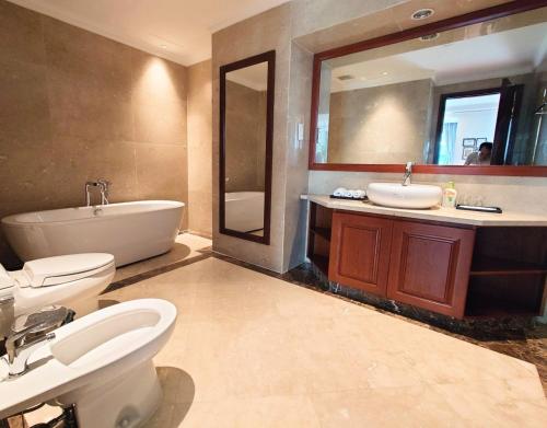 een badkamer met 2 wastafels, een bad en een toilet bij The Rixx Vincom Center in Ho Chi Minh-stad