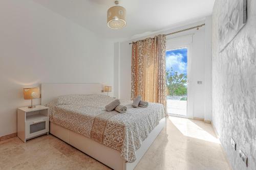 a white bedroom with a bed and a large window at Ocean view Family Apartment in Playa La Arena in Puerto de Santiago