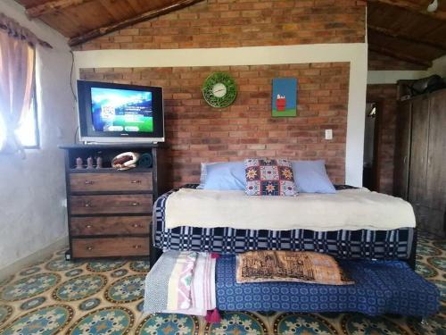 a bedroom with a bed and a tv on a brick wall at Mountain Cabin - Nature and Relax in Fúquene