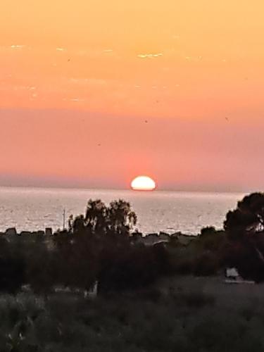 a sunset over the ocean with the sun in the horizon at La Foggia seaside paradise in Siculiana