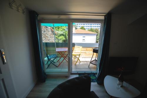 Cette chambre dispose d'une porte s'ouvrant sur un balcon avec une table et des chaises. dans l'établissement Lova Spa Saint-Etienne, à Saint-Étienne