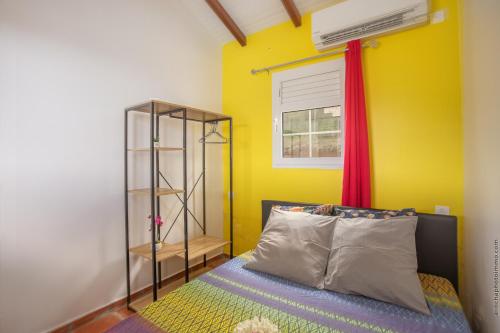 a bedroom with a bed and a yellow wall at Bungalow avec piscine au cœur de la campagne Vert in Sainte-Marie