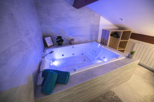 a large white tub in a bathroom with purple walls at Lova Spa Saint-Etienne in Saint-Étienne